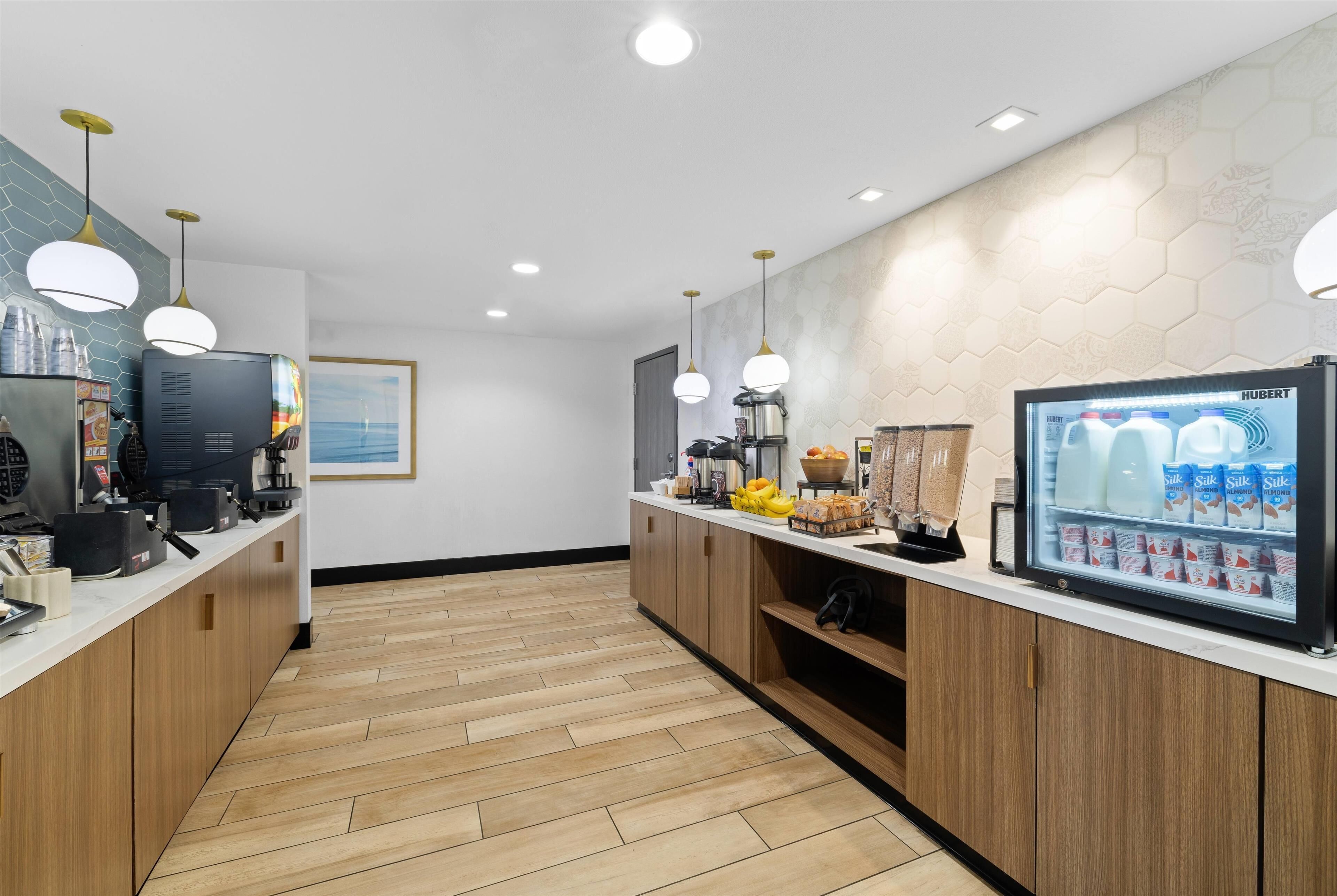 A modern kitchen with wooden cabinets, a coffee machine, a refrigerator, and a milk display.