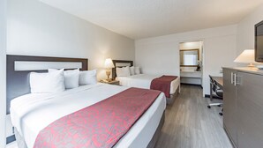 A hotel room with two beds, a desk, and a mirror. - MC Pacific Inn & Suites (Torrance)