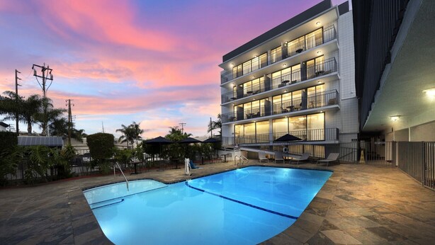 A hotel with a swimming pool, multiple balconies, and a modern architectural design. - MC Pacific Inn & Suites (Torrance)