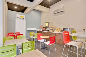 A breakfast area with a Daybreak sign, colorful chairs, a counter with food items, and a television.