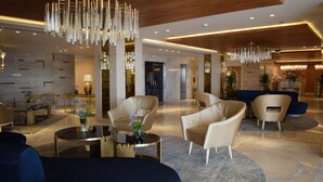 A modern lobby with a marble floor, leather sofas, and a central chandelier. - Romance Alexandria Hotel (Alexandria)