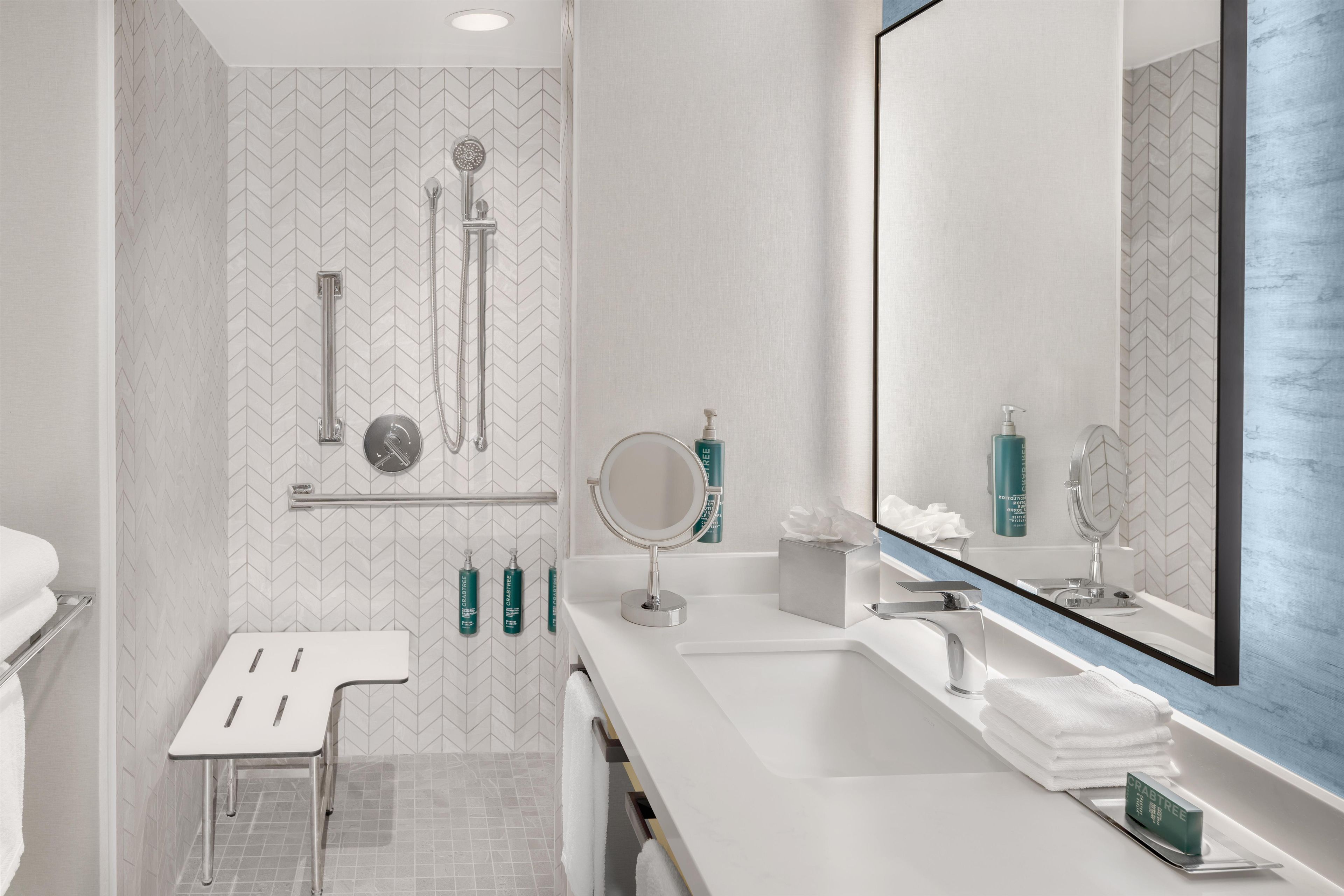 A modern bathroom with a white vanity, a large mirror, and a shower with a handheld showerhead.