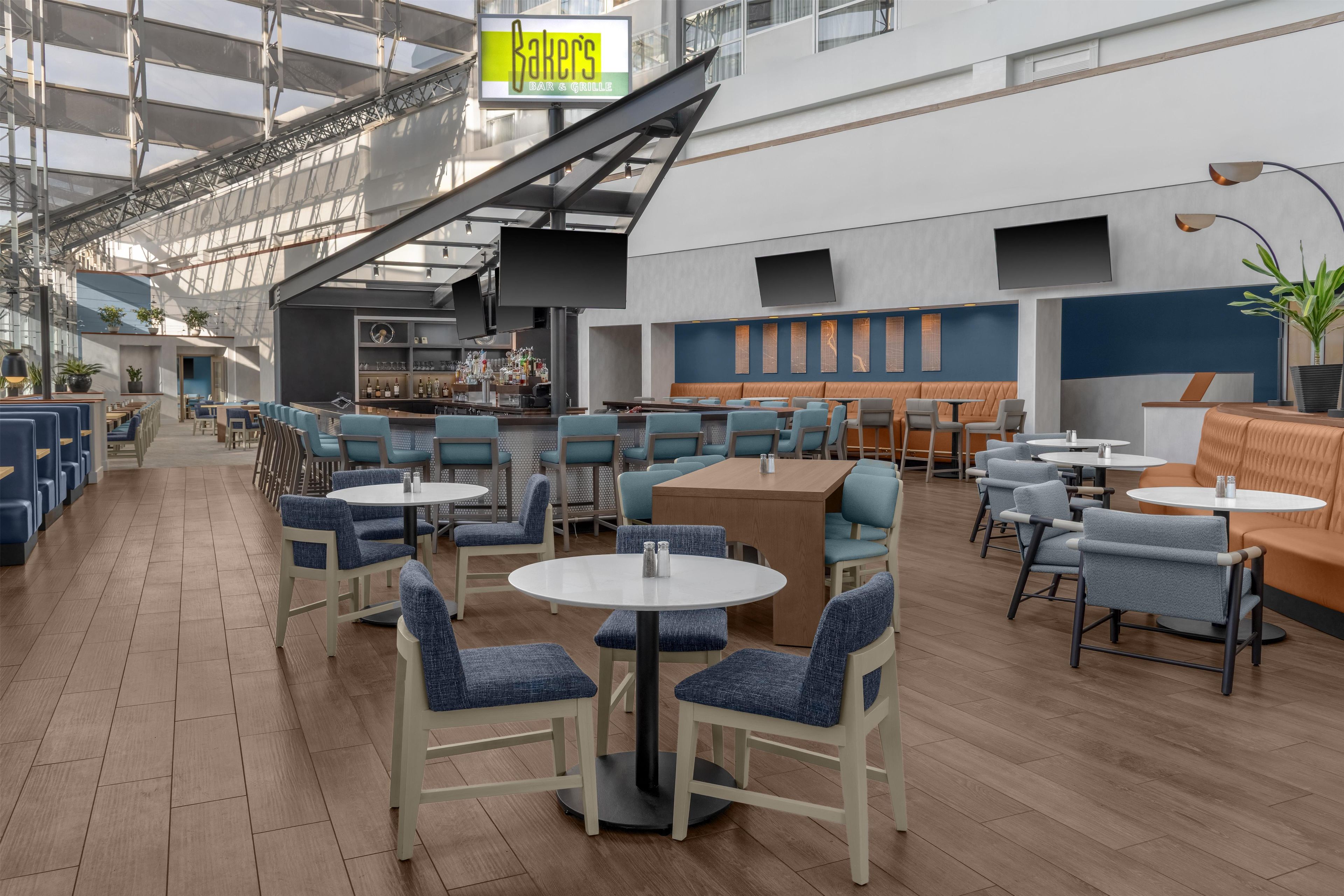 A spacious indoor dining area with multiple seating arrangements, including tables and booths, and a bar area with a counter and bar stools.