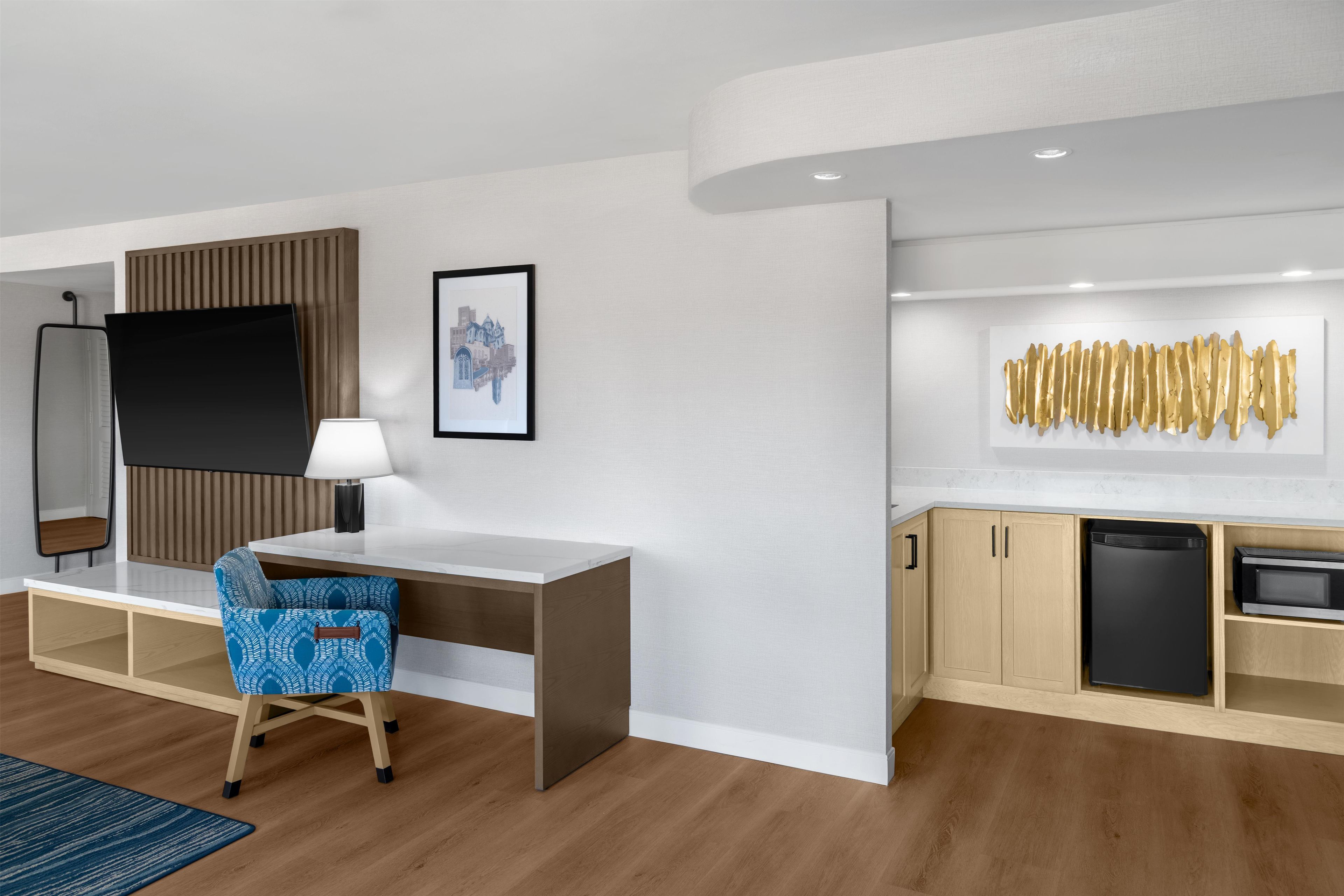 Una habitación de hotel moderna con escritorio, silla y kitchenette.