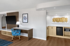 A modern hotel room with a desk, chair, and kitchenette. - Doubletree Hotel South Bend (South Bend)