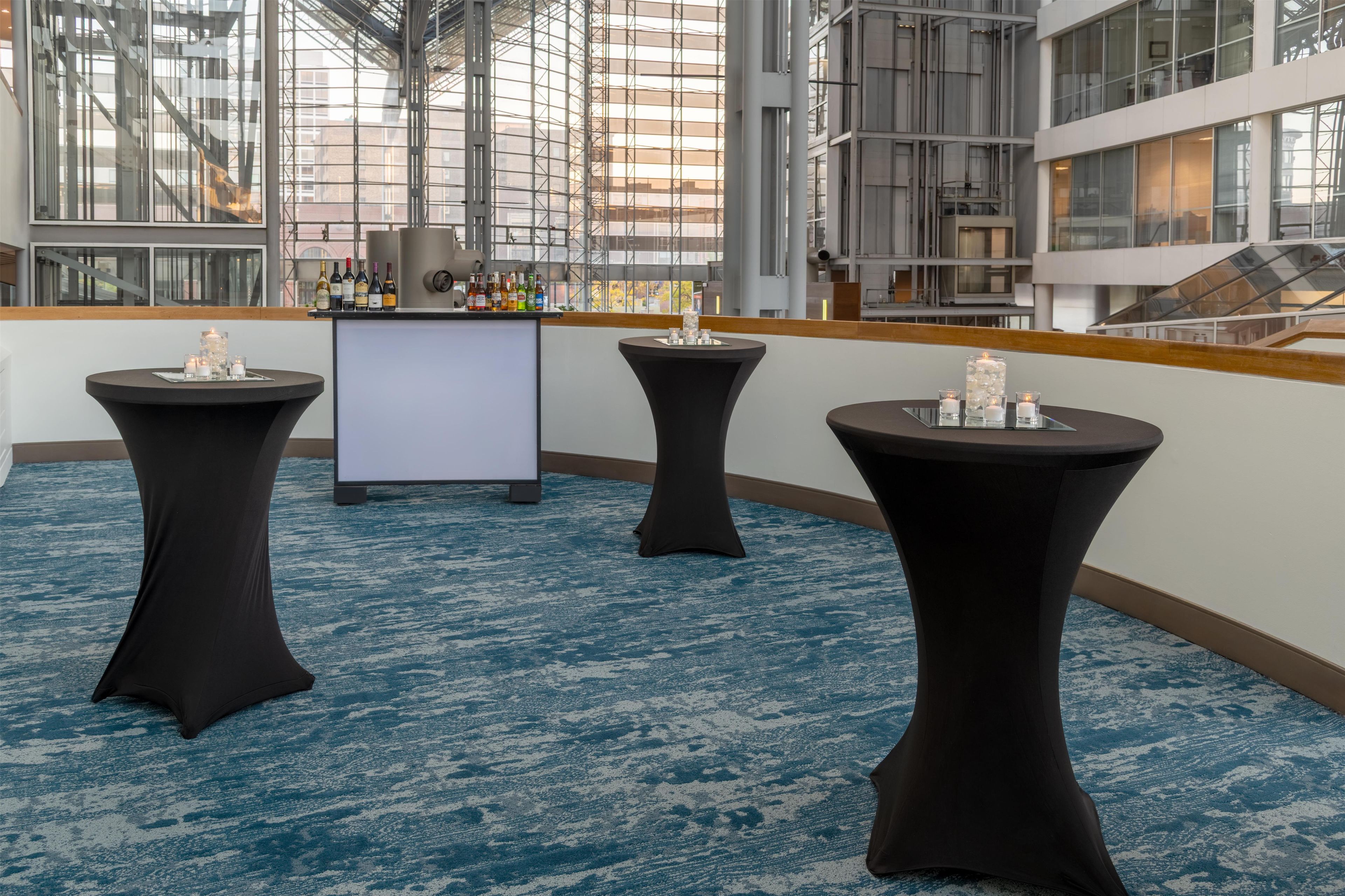 A modern hotel lobby with a bar area, three round tables, and a large screen.