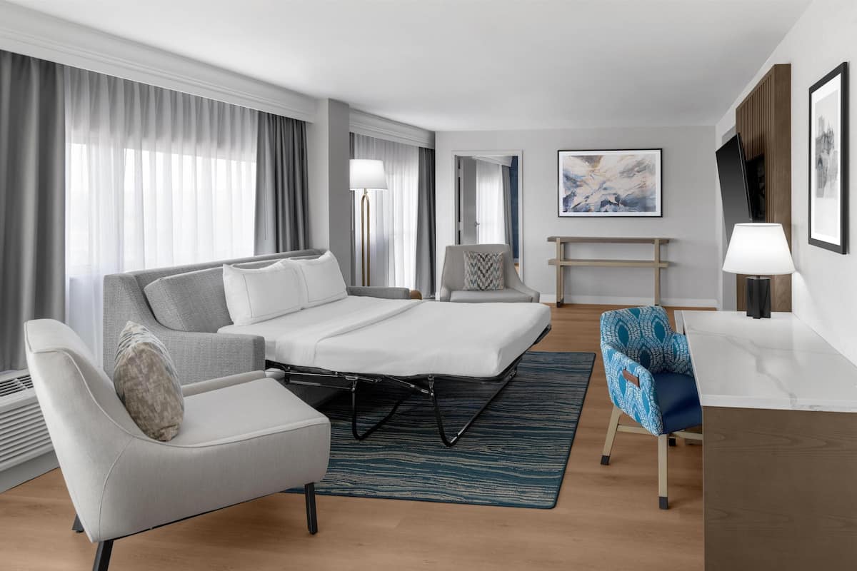 Ein modernes Hotelzimmer mit Bett, Sofa, Schreibtisch und Stuhl.