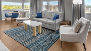A modern living room with a grey sofa, blue armchairs, a white coffee table, and a blue patterned rug.