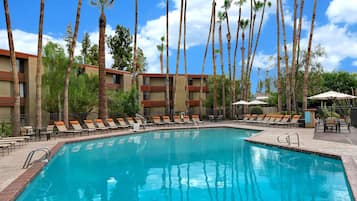 Relax by the serene pool surrounded by palm trees and lounge chairs.