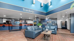 A Travelodge lobby with a reception desk, seating area, and vending machine. - Travelodge by Wyndham Rapid City (Rapid City)