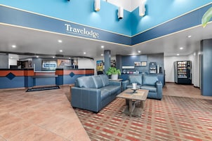 Un hall d’hôtel Travelodge comprenant un comptoir d’accueil, un espace salon et un distributeur automatique.