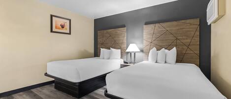 Habitación de hotel con dos camas, una mesita de noche, una lámpara y un cuadro en la pared.