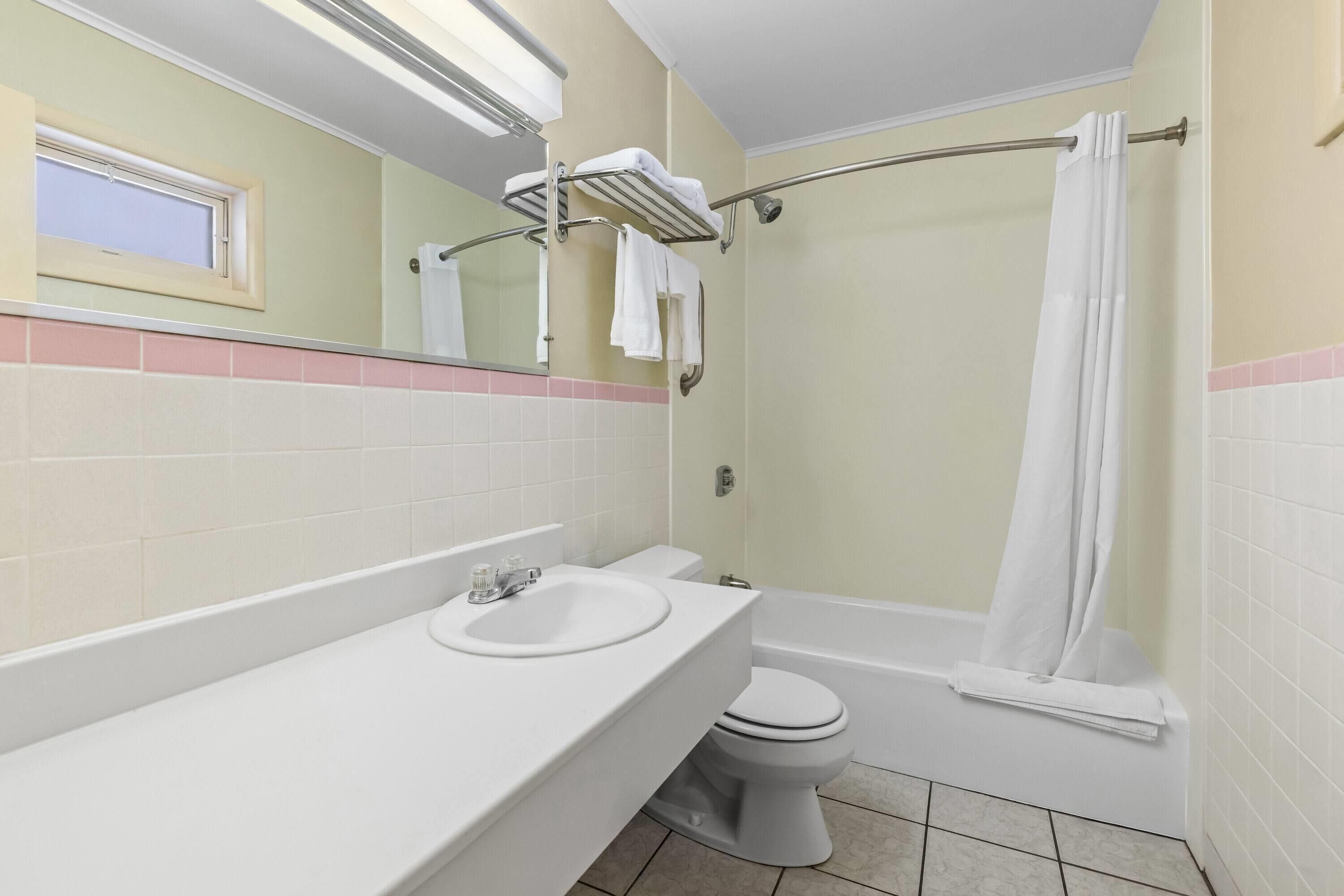 A bathroom with a sink, toilet, bathtub, and a shower curtain.