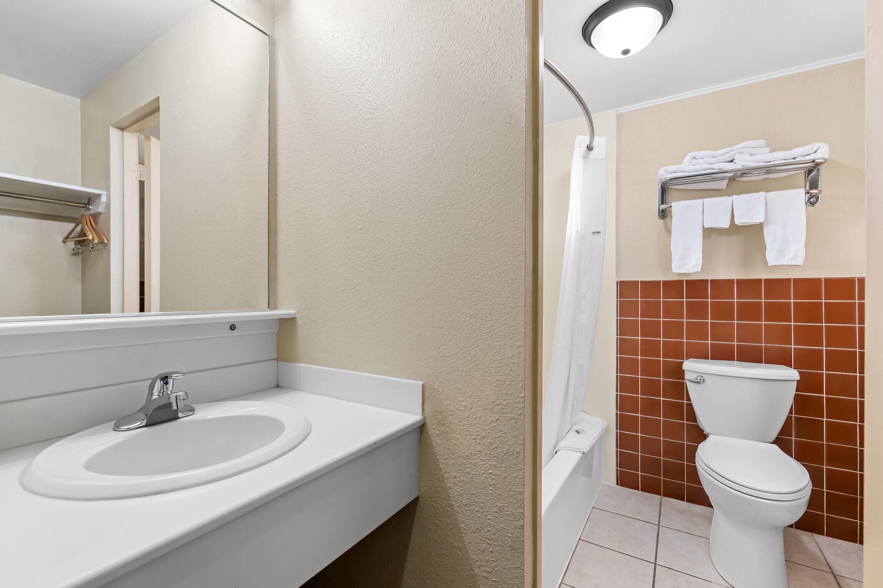 Un baño con lavamanos, espejo, inodoro y toallero.