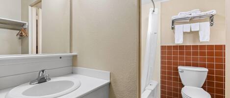 Un baño con lavamanos, espejo, inodoro y toallero.