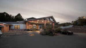 A building with a covered entrance, a sign indicating 'Travelodge,' and a parking area with cars. - Travelodge by Wyndham Rapid City (Rapid City)