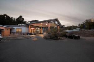 Un bâtiment doté d’une entrée couverte, d’une enseigne indiquant « Travelodge », et d’un espace de stationnement avec des voitures.