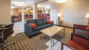 A hotel lobby with a sofa, chairs, a table, and a patterned carpet.
