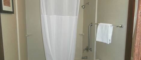 Een standaard badkamer met bad, toilet en een handdoekrek.