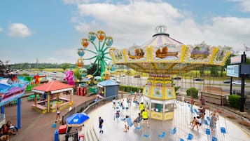 A carousel with a colorful canopy, surrounded by a fenced area with blue chairs and a small building.