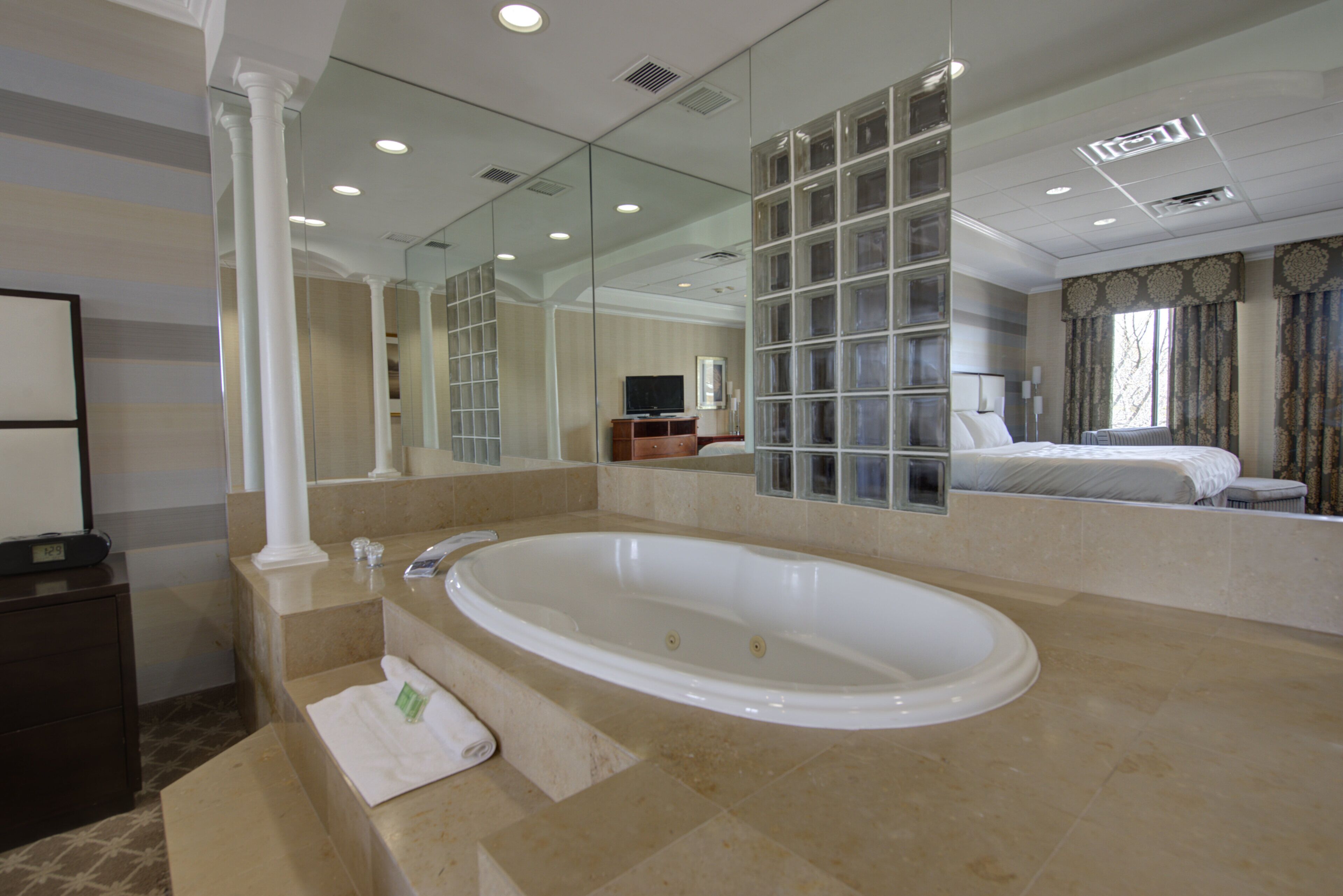 Un baño moderno con una bañera independiente grande, un espejo y un televisor.