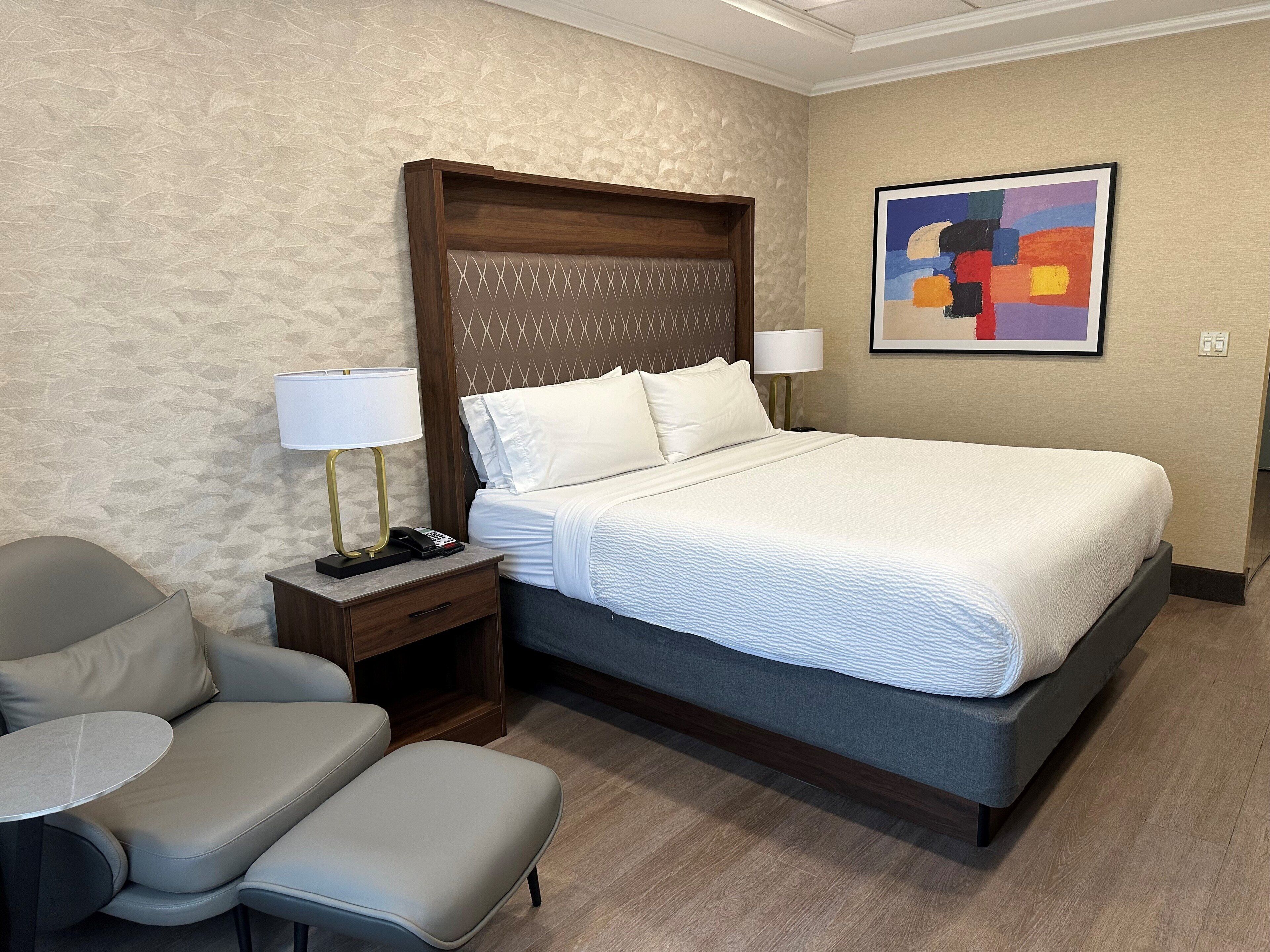 Une chambre d’hôtel avec un grand lit, un bureau avec une lampe, une chaise et une petite table.