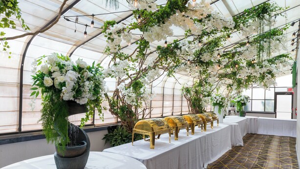 A greenhouse venue with tables, chairs, and floral decorations. - Holiday Inn Plainview-Long Island by IHG (Plainview)