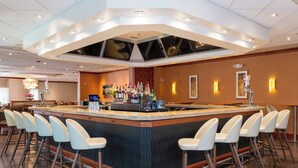 A bar area with a central island, bar stools, and a variety of bottles. - Holiday Inn Plainview-Long Island by IHG (Plainview)