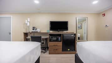 A hotel room with two beds, a desk with a computer, a microwave, and a refrigerator.