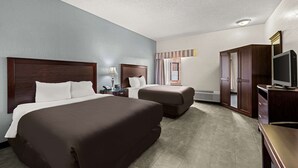 A hotel room with two beds, a TV, a wardrobe, and a window with curtains. - Suburban Studios Kansas City Airport North (Platte City)