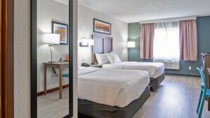 A hotel room with two beds, a desk with a lamp, a chair, and a window with curtains. - Quality Inn Milan - Sandusky (Milan)