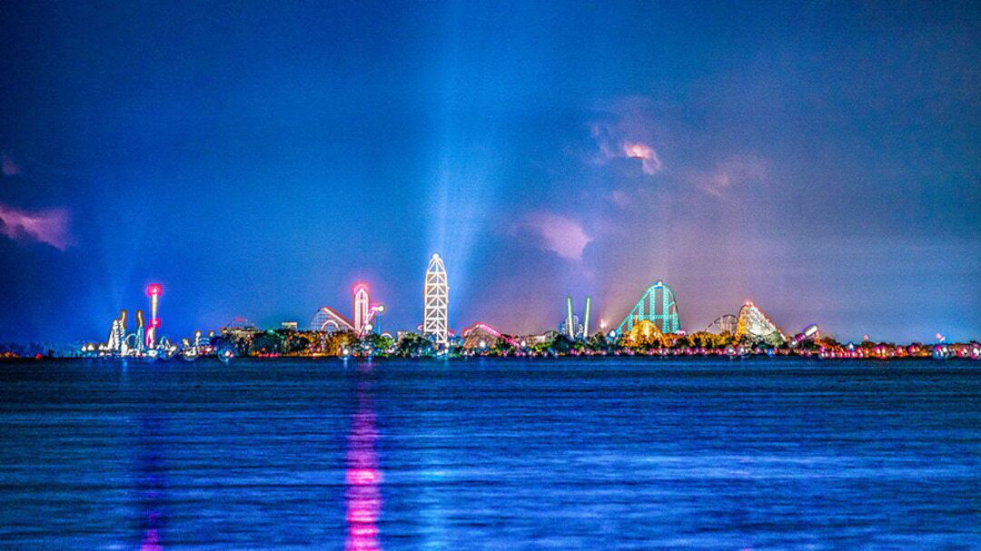 A nighttime view of a waterfront with illuminated structures and a clear reflection on the water.