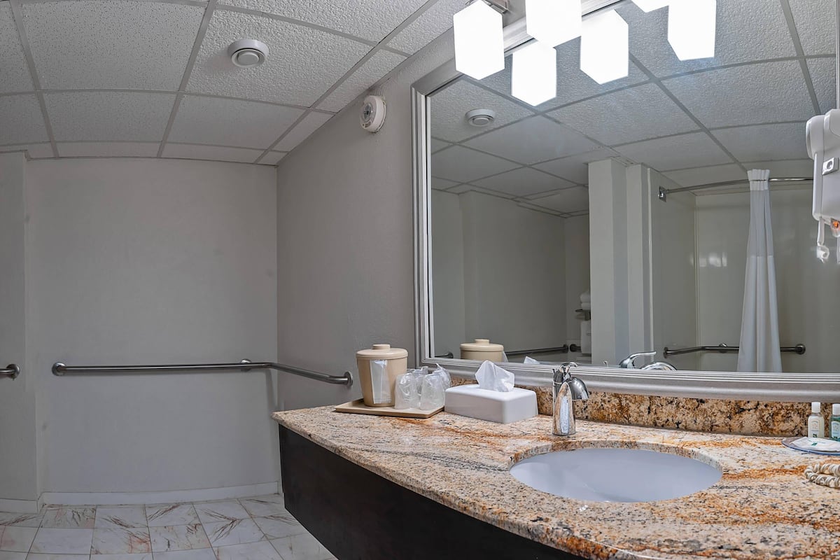 A modern bathroom with a granite countertop, a sink, a mirror, and a hand dryer.