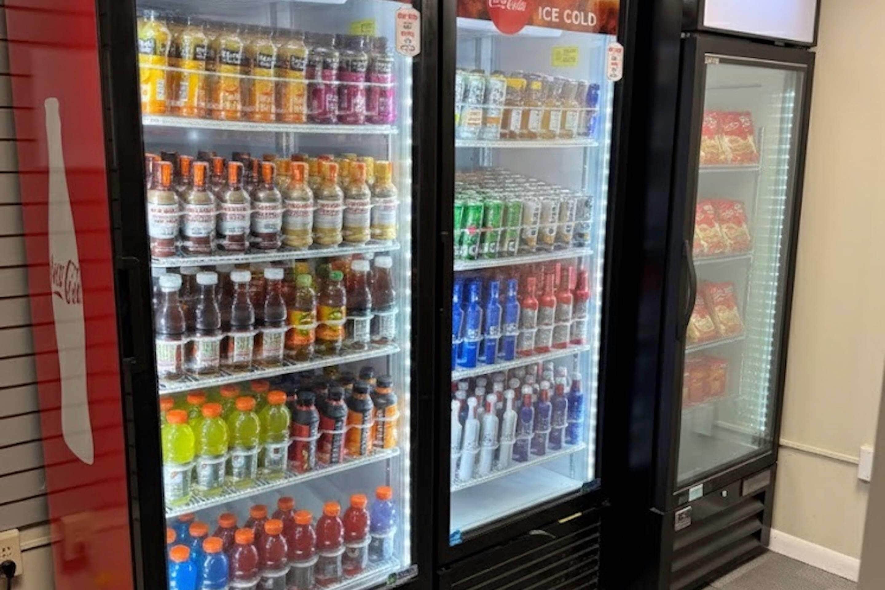 A beverage refrigerator stocked with various drinks, including sodas, juices, and water bottles.