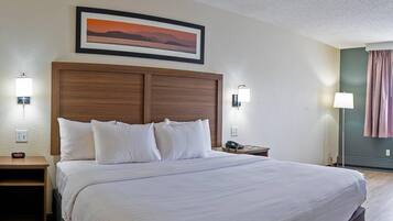 A neatly made bed with white linens, a wooden headboard, and two bedside lamps.