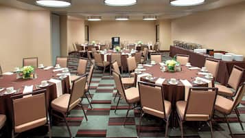 A conference room with multiple tables, chairs, and a buffet setup.