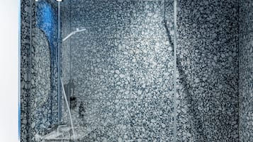 A modern shower enclosure with a pebble-textured wall and a glass door.