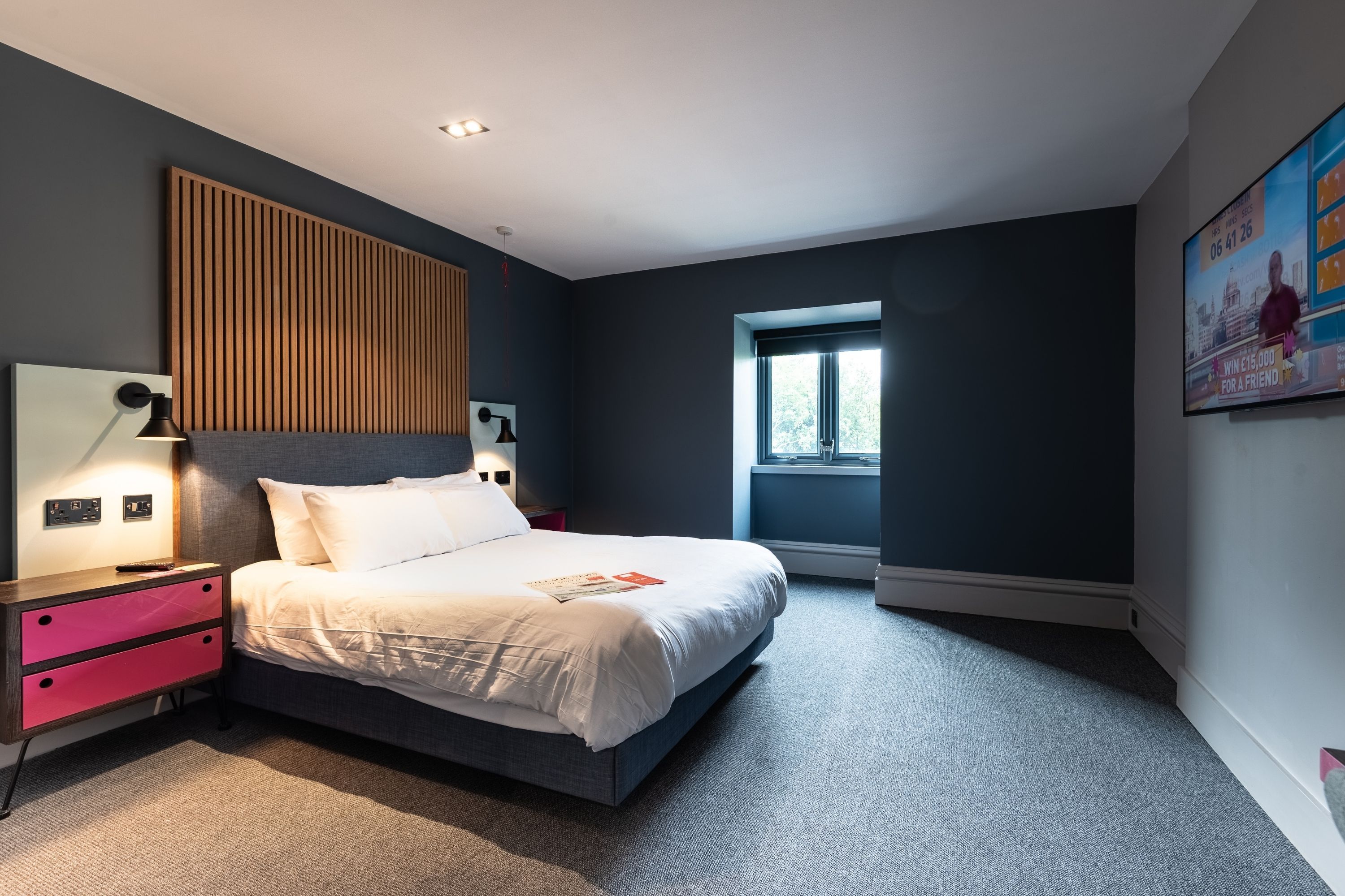 Un dormitorio moderno con cama, mesitas de noche y una ventana.