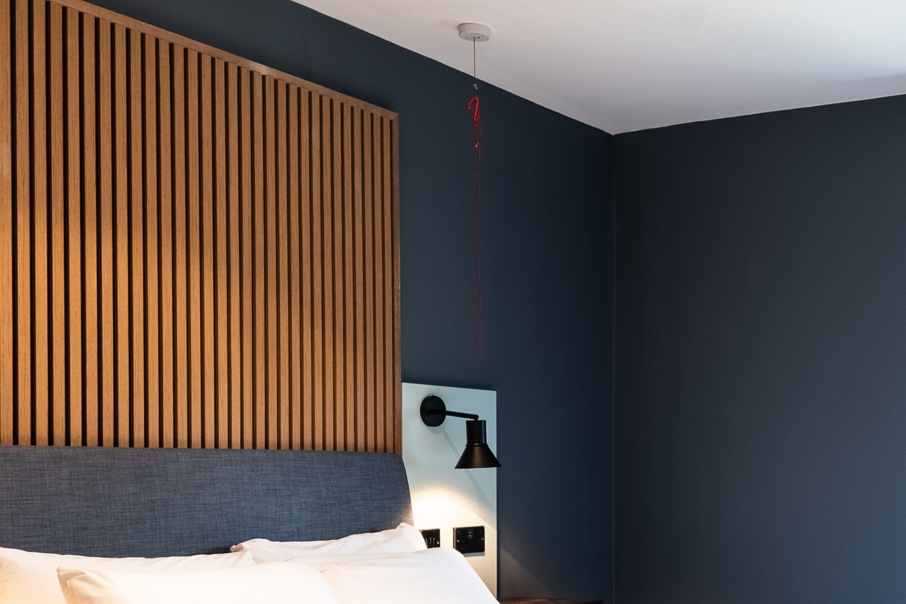 Un dormitorio con una cama, una lámpara de pared y un accesorio de techo rojo.