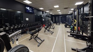 A gym with weightlifting equipment, benches, and dumbbells. - Village Hotel Warrington (Warrington)