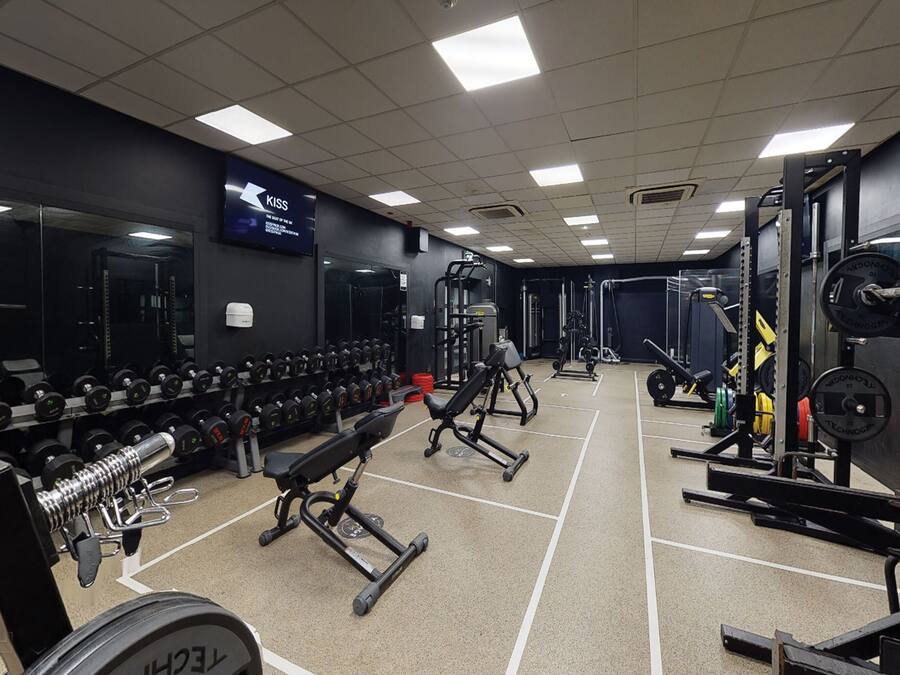 A gym with weightlifting equipment, benches, and dumbbells.