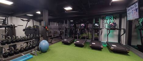 A gym with treadmills, kettlebells, and exercise balls.