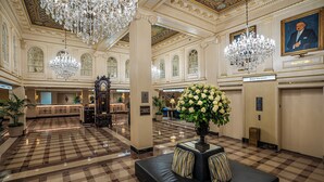 A lobby with a checkered floor, chandeliers, a reception desk, and a large floral arrangement. - Hotel Monteleone, New Orleans (New Orleans)