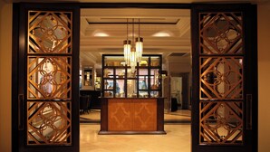An open doorway with intricate wooden designs, a central light fixture, and a reflective surface behind it. - Hotel Monteleone, New Orleans (New Orleans)