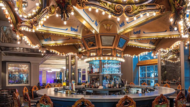 A bar area with ornate mirrors, a central bar counter, and bar stools with animal designs. - Hotel Monteleone, New Orleans (New Orleans)