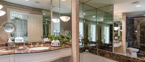 A luxurious bathroom with a large marble sink, a freestanding bathtub, and a large mirror reflecting the room.