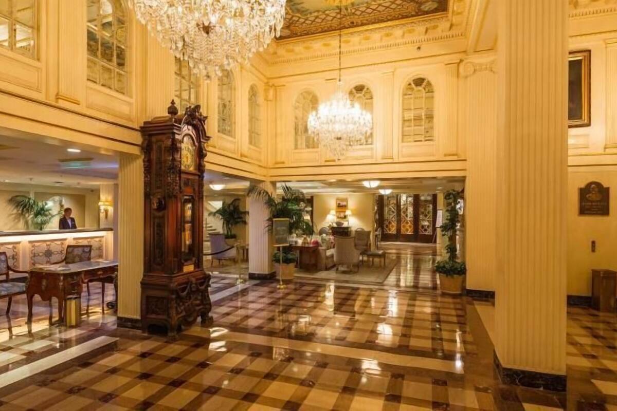 A spacious lobby with a checkered floor, ornate chandeliers, and a grand clock.