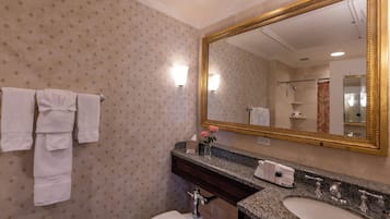 Un baño con un espejo grande, dos lavamanos, un inodoro y toallas colgadas en un perchero.