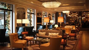 A spacious lobby with leather armchairs, sofas, and tables, featuring large windows and a chandelier. - Hotel Monteleone, New Orleans (New Orleans)