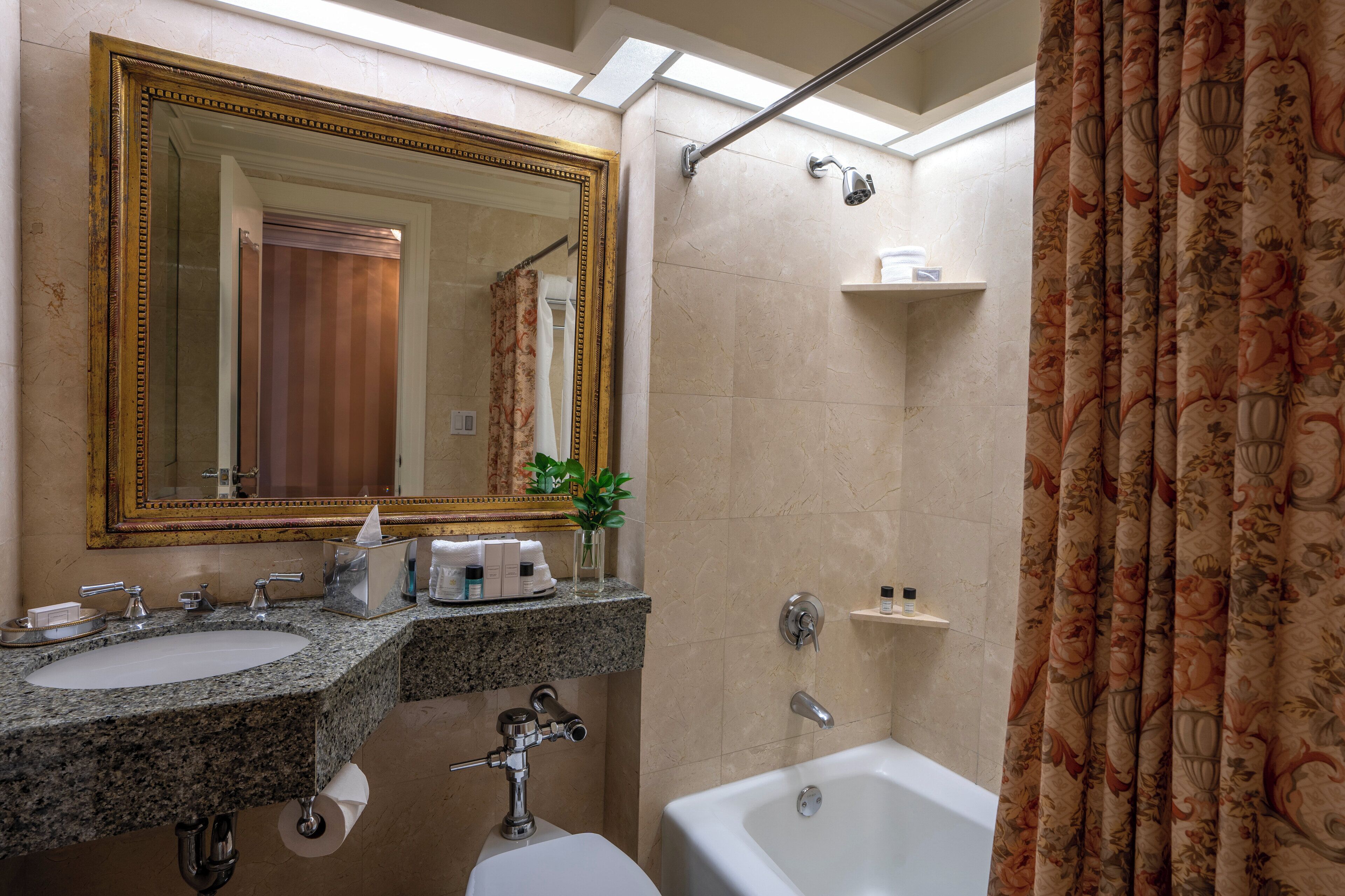 Un baño con un espejo grande, dos lavamanos, una bañera y una cortina de ducha.